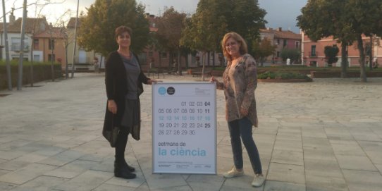 La regidora d'Innovació i Gestió del Coneixement, Marta Roman, i la responsable tècnica d'El Mirador, Carme Guirao, amb el cartell de la Setmana de la Ciència.