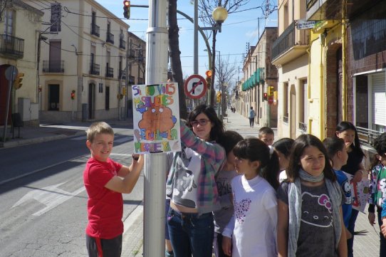 Alumnes castellarencs penjant cartells de sensibilització sobre la recollida de caques de gos