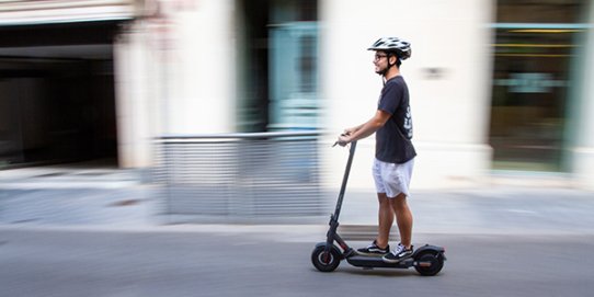 Un usuari circulant amb un vehicle de mobilitat personal (VMP) en un espai urbà.